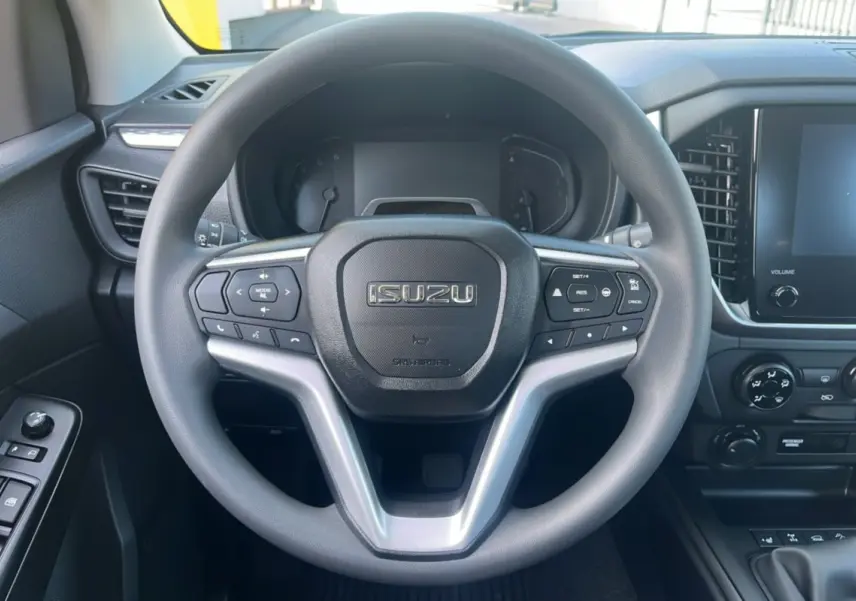 Vue intérieure centrée sur le volant multifonctions ISUZU du D-MAX 2026 avec tableau de bord et écran tactile.