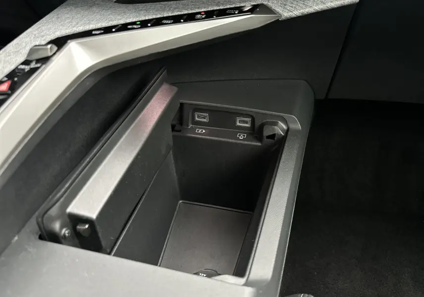 Gros plan sur la console centrale du Peugeot 3008 Hybrid 2024 avec ports USB-C et prise 12V intégrés.