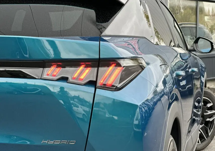 Feu arrière droit allumé sur Peugeot 3008 Hybrid 2024 bleu Obsession, vue 3/4 arrière côté droit.