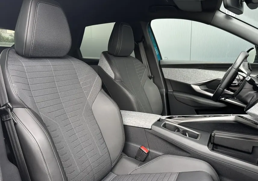 Intérieur du Peugeot 3008 Hybrid 2024, vue côté conducteur, sièges tissu gris avec surpiqûres claires et console centrale.