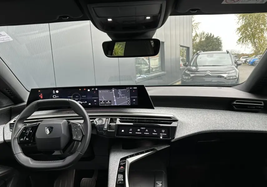 Vue intérieure avant du Peugeot 3008 Hybrid 2024 avec tableau de bord numérique panoramique et volant compact noir.