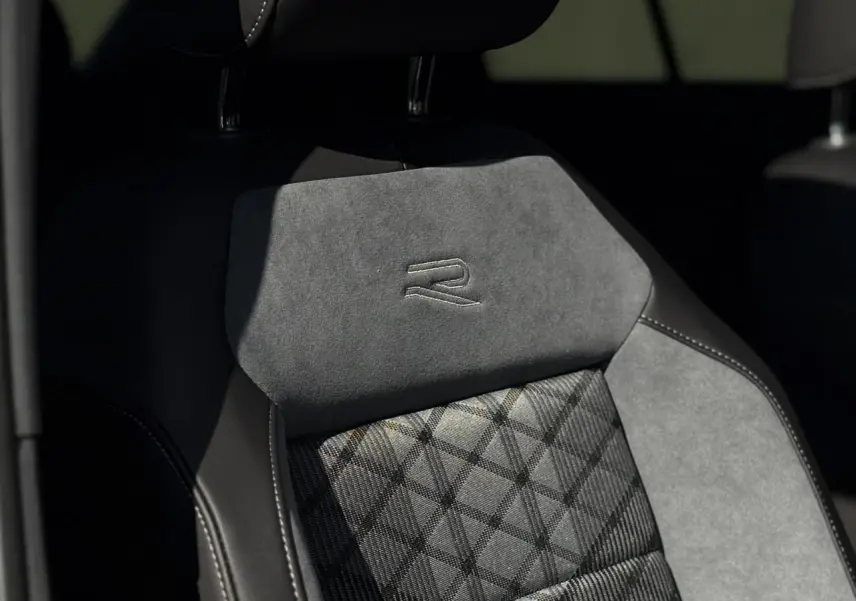 Gros plan sur le siège avant gris et noir du Volkswagen T-Roc R-Line 2025 avec logo R brodé sur l'appuie-tête.