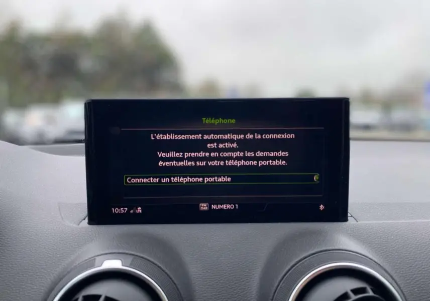 Écran central de l'Audi Q2 2023 affichant la connexion automatique d'un téléphone, avec tableau de bord gris.