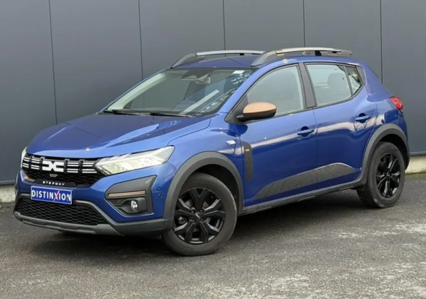 Vue 3/4 avant droite de la Dacia Sandero Stepway Bleu Iron avec jantes noires et barres de toit gris Mégalithe.