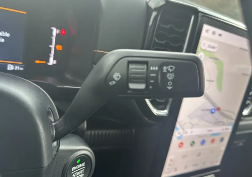 Gros plan sur le commodo de commande d’essuie-glace et le bouton start/stop du Ford Ranger Wildtrak 2025, intérieur noir.