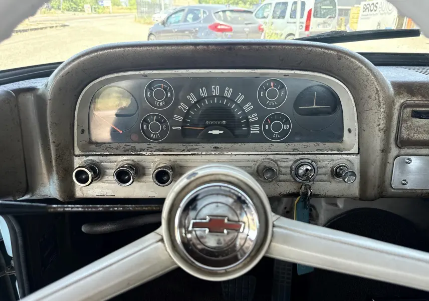 Tableau de bord vintage beige avec compteurs ronds et volant Chevrolet, intérieur d’un C10 Apache 1963 visible de face.