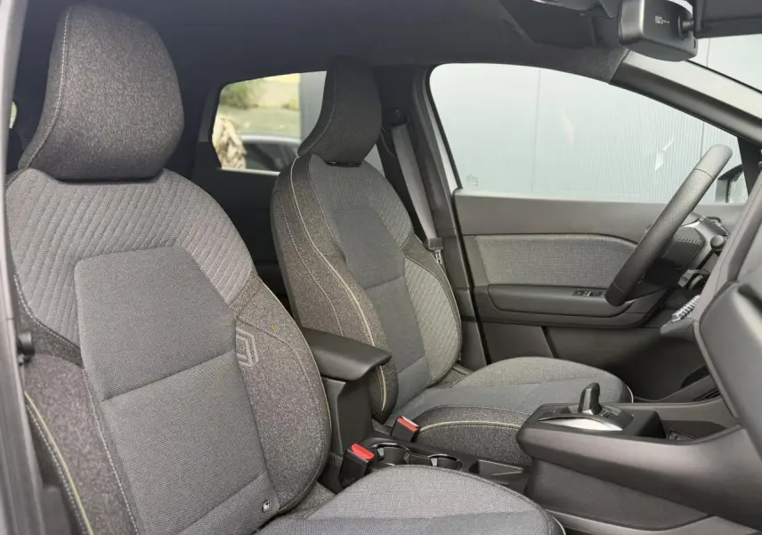 Vue intérieure côté droit du Renault Captur gris Rafale, mettant en valeur les sièges tissu et la console centrale avec accoudoir.