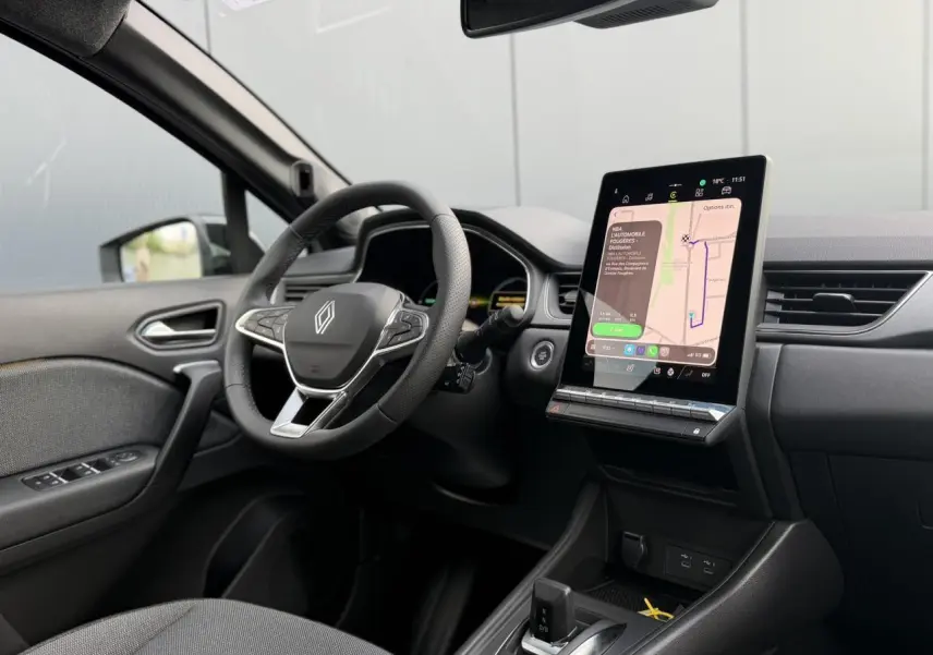 Vue intérieure côté conducteur du Renault Captur gris, avec volant multifonction et grand écran tactile vertical au tableau de bord.