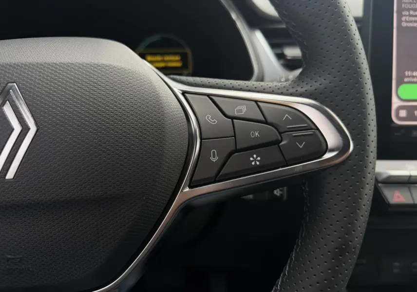 Gros plan sur le volant perforé noir du Renault Captur 2026 avec commandes multifonctions côté droit et logo central.