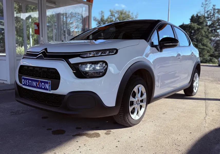 Citroën C3 blanc vue 3/4 avant droit, avec toit noir et protections noires autour des roues.