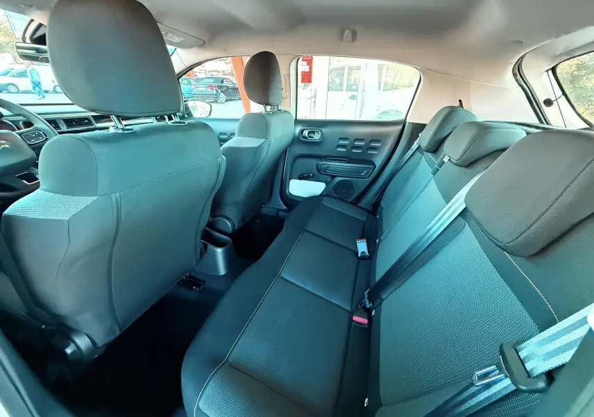 Vue intérieure arrière droite de la Citroën C3 blanche 2021, montrant les sièges arrière en tissu gris foncé.