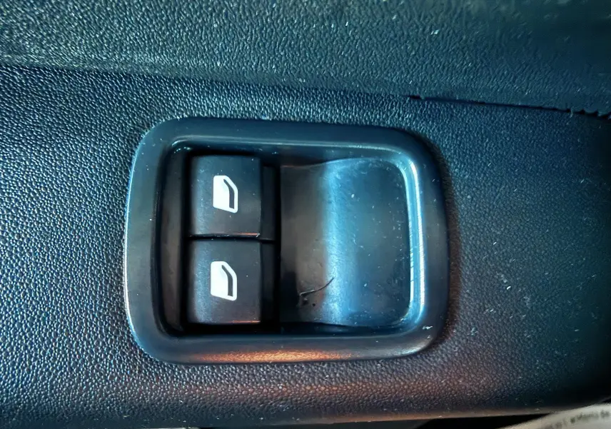 Boutons de commande des vitres électriques sur la portière intérieure d'une Citroën C3 blanche de 2021.