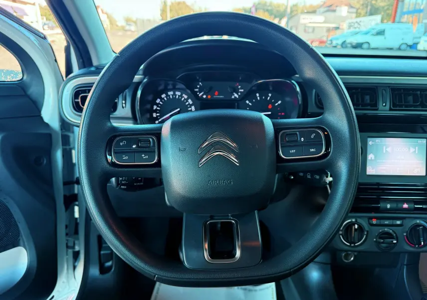 Vue centrée sur le volant noir du Citroën C3 blanc, avec tableau de bord et écran tactile visibles à droite.