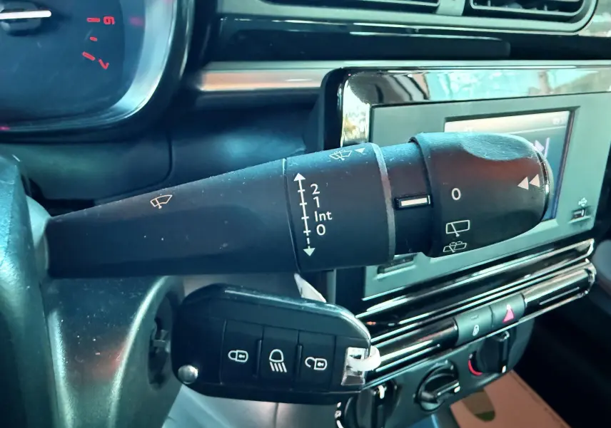 Gros plan sur la commande d'essuie-glace à gauche du volant dans l'habitacle d'une Citroën C3 blanche de 2021.