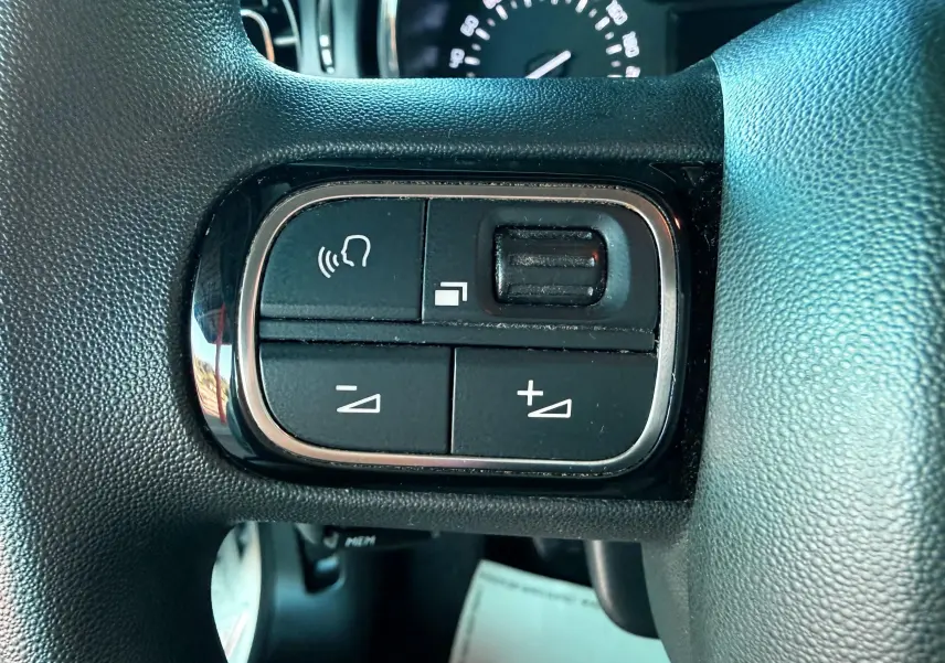 Gros plan sur les commandes de volume vocal et audio au volant d'une Citroën C3 blanche de 2021.