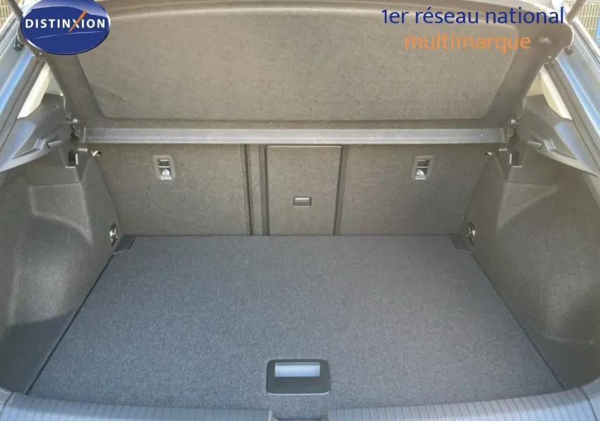 Coffre ouvert vu de l'arrière d'un Volkswagen T-Roc gris pyrite, montrant un espace de chargement propre et spacieux.