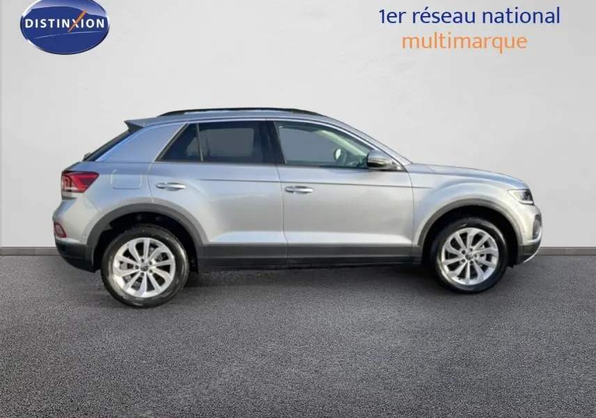 Vue de profil côté gauche d'un Volkswagen T-Roc gris pyrite métal 2025 sur fond clair, avec jantes alliage visibles.
