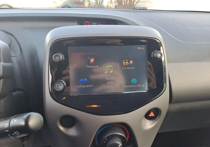 Écran tactile central avec menu audio et téléphone sur tableau de bord gris du Peugeot 108 noir 2020.