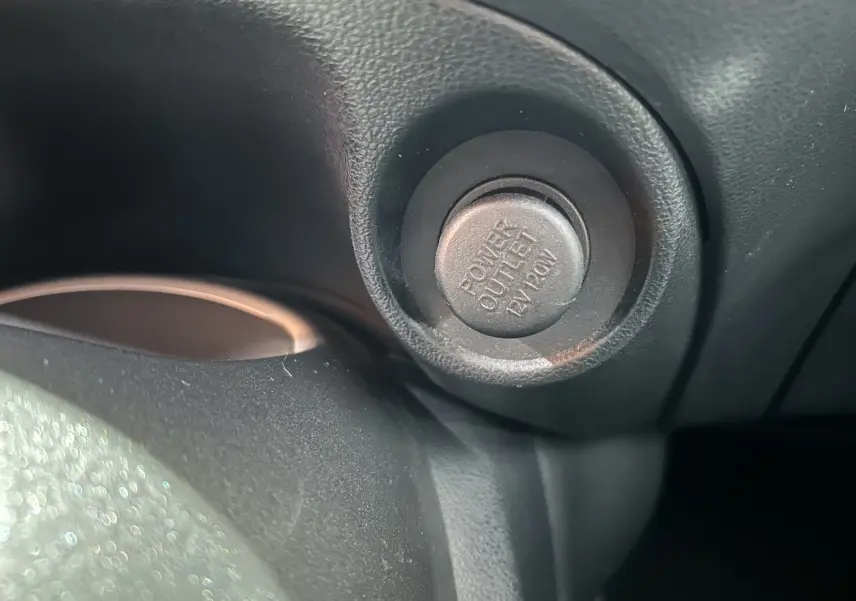 Gros plan sur la prise 12V Power Outlet du tableau de bord intérieur du Nissan Juke noir métal de 2012.