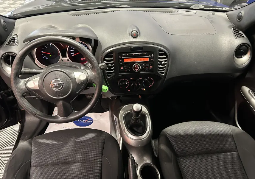 Vue intérieure frontale du tableau de bord et volant noir du Nissan Juke dci 110 Acenta avec boîte manuelle et sièges tissu noirs.