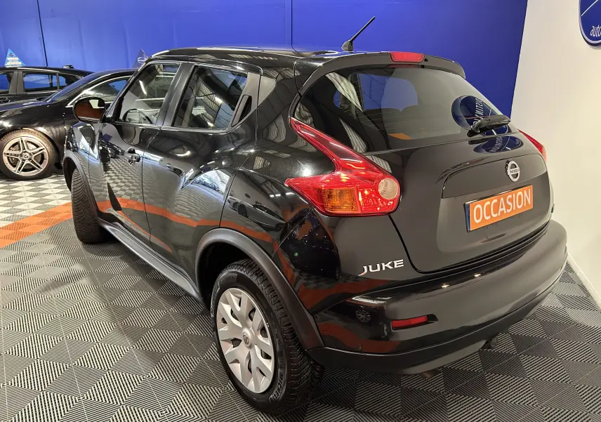 Vue 3/4 arrière droite d'un Nissan Juke noir métal avec attelage, en intérieur sur sol à damier gris et orange.