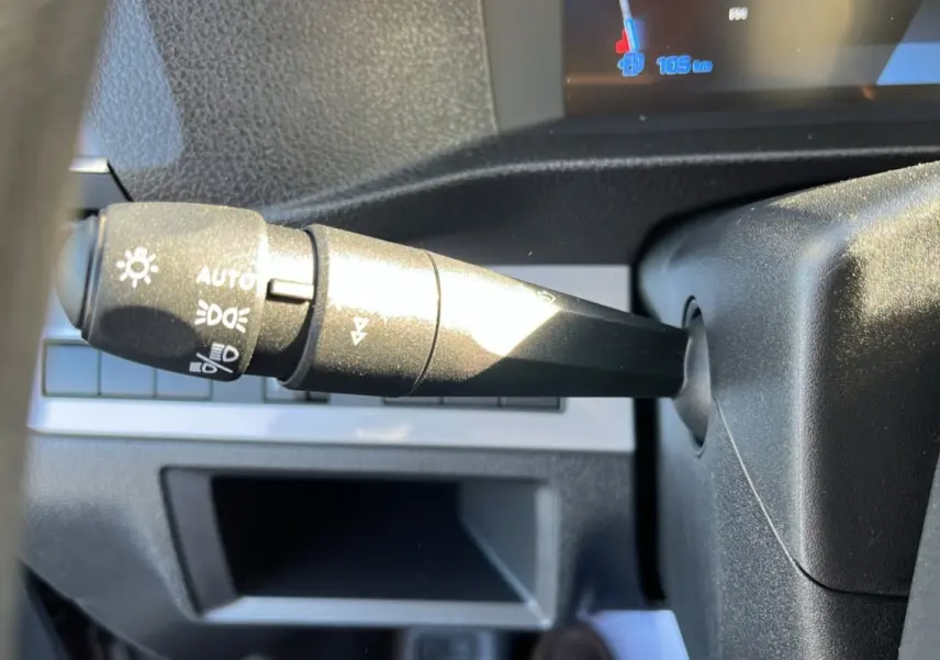 Gros plan sur la commande des feux au volant du Peugeot Traveller gris acier 2025, avec affichage numérique partiel.