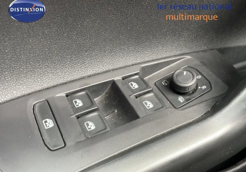 Gros plan sur les commandes de lève-vitres et réglage des rétroviseurs côté conducteur d'une Volkswagen Polo blanche.