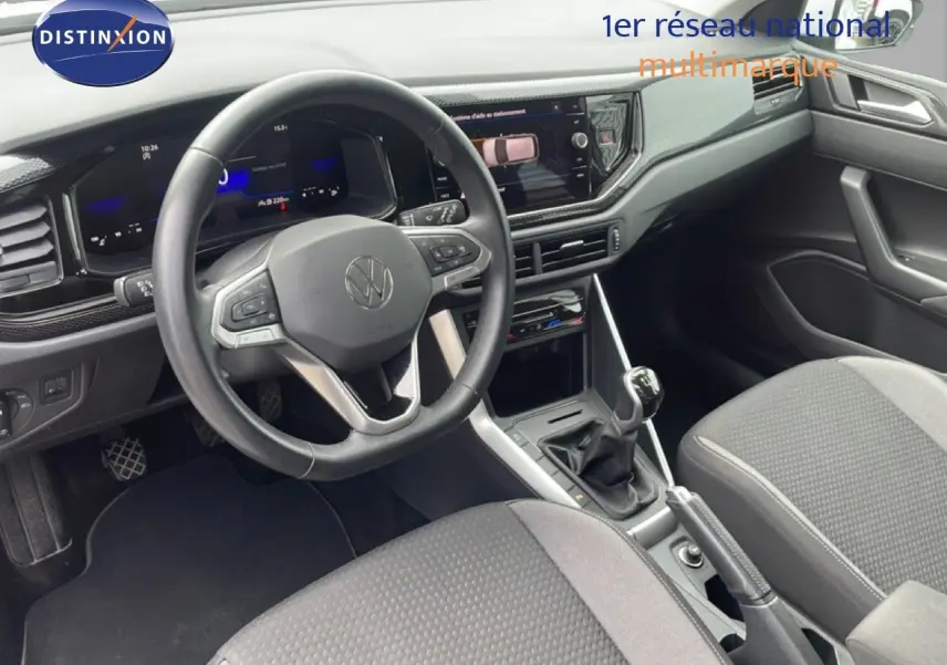 Vue intérieure de la Volkswagen Polo 2022, tableau de bord et volant multifonction en cuir, sièges tissu gris.