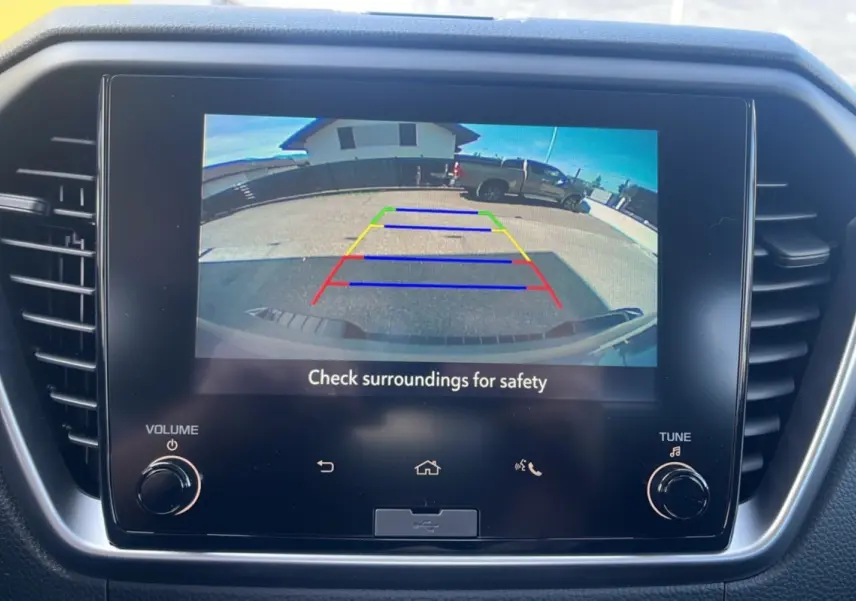 Écran tactile intérieur montrant la caméra de recul avec vue arrière sur un Isuzu D-MAX gris Kinabalu en stationnement.