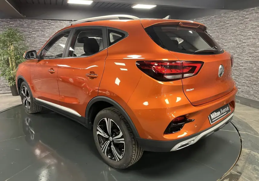 Vue 3/4 arrière droite du SUV MG ZS orange métallisé avec jantes alliage noires et feux arrière LED.