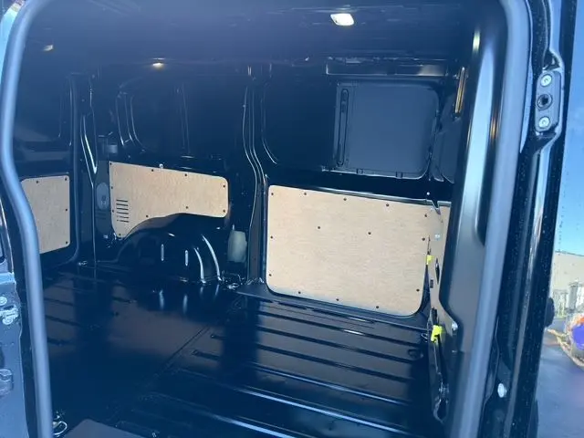 Vue intérieure arrière du Peugeot Expert Fourgon noir 2025, montrant l'espace de chargement vide avec panneaux de protection en bois.