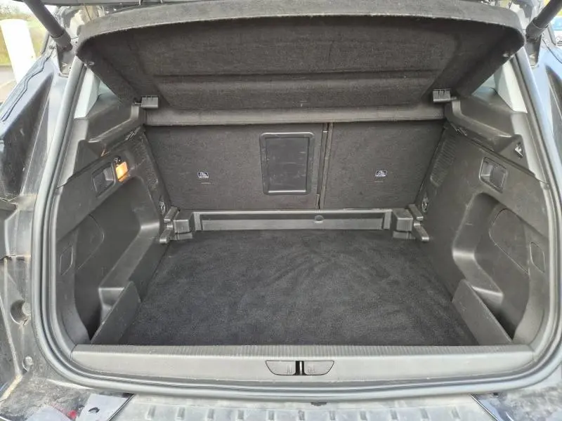 Coffre ouvert vu de l'arrière d'un Opel Grandland X noir diamant, montrant un espace de chargement propre et bien aménagé.