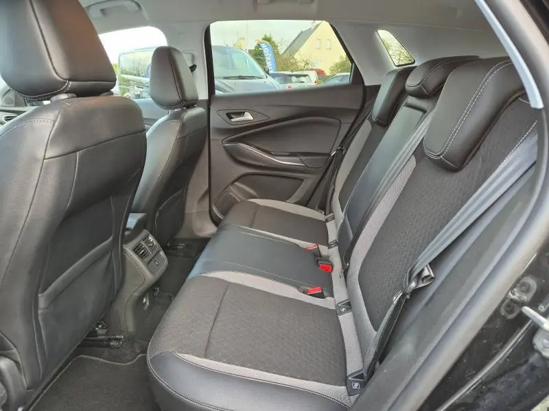 Vue intérieure arrière droite de l’Opel Grandland X 2020 noir diamant, sièges en tissu et cuir avec appuie-têtes intégrés.