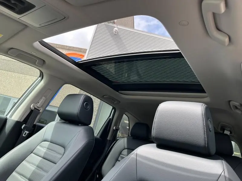 Vue intérieure du Honda CR-V 2024 montrant les sièges en cuir noir et le toit panoramique en verre ouvert.