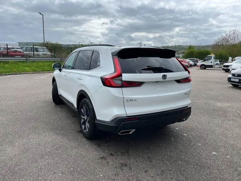 Vue 3/4 arrière droite du Honda CR-V blanc platine nacré 2024 avec feux arrière LED et double sortie d'échappement chromée.