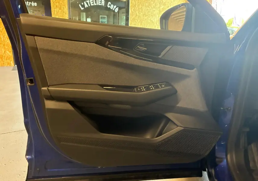 Vue de profil intérieur sur la porte avant gauche bleu du Renault Austral 2024 avec commandes de vitres et haut-parleur intégré.