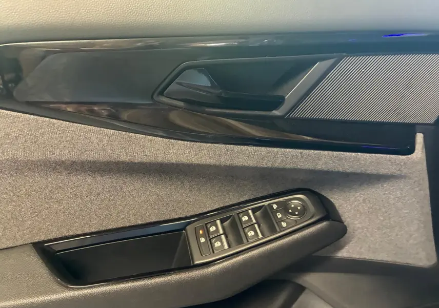 Gros plan sur la porte intérieure côté conducteur du Renault Austral 2024, tissu gris et commandes de vitres noires.