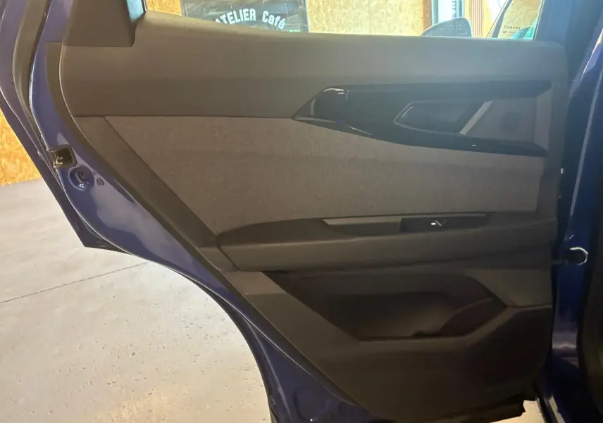 Vue rapprochée de la porte arrière droite bleu du Renault Austral 2024, montrant le revêtement tissu gris et les commandes.
