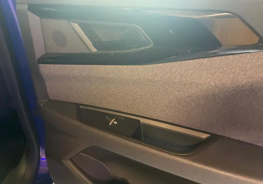 Détail de la porte avant gauche du Renault Austral bleu 2024, montrant le revêtement tissu gris et la commande de vitre électrique.