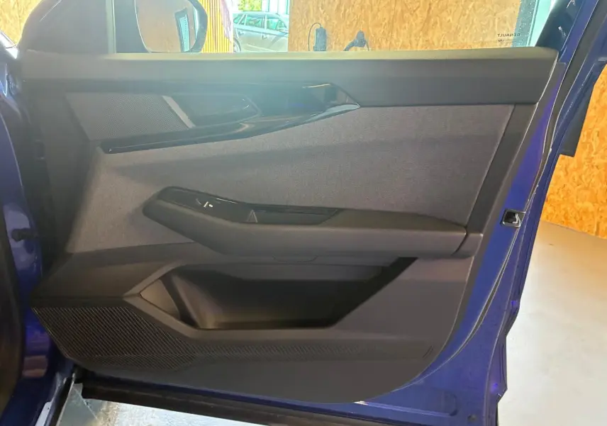 Vue intérieure de la porte avant gauche du Renault Austral bleu 2024, avec habillage tissu gris et garnitures noires.