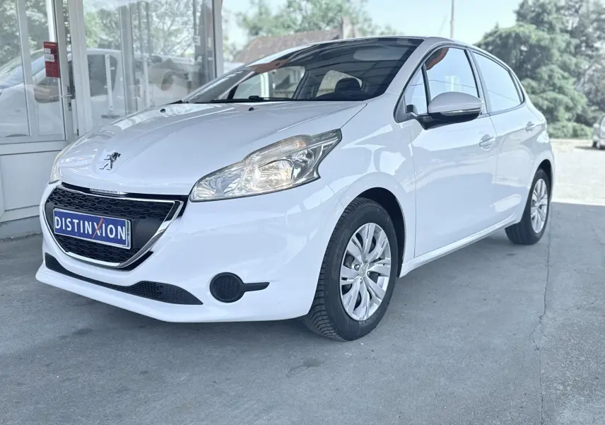 Peugeot 208 blanche vue en 3/4 avant droit, avec calandre noire et jantes alliage, stationnée devant un bâtiment vitré.