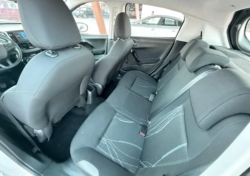 Vue intérieure côté droit montrant les sièges arrière en tissu noir avec motifs gris d'une Peugeot 208 blanche de 2013.