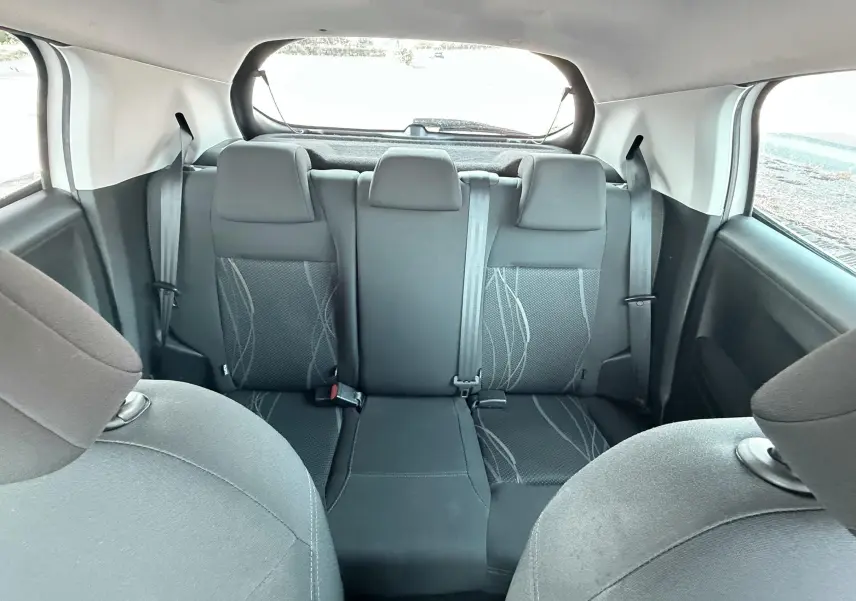 Vue intérieure arrière montrant les sièges arrière noirs avec motifs gris d'une Peugeot 208 blanche de 2013.