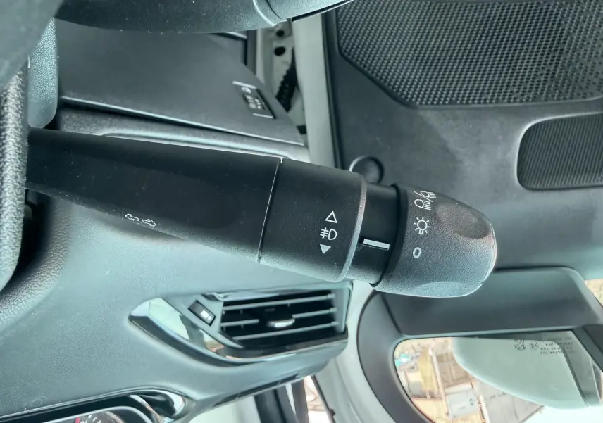 Gros plan sur la commande des phares et clignotants côté gauche dans l’habitacle d’une Peugeot 208 blanche de 2013.