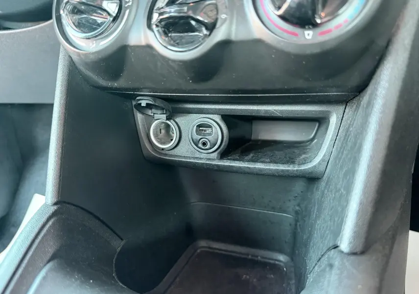 Vue rapprochée de la console centrale noire du Peugeot 208 2013, montrant prises USB et allume-cigare ouverts.