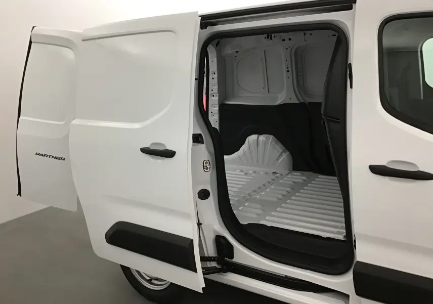 Vue latérale droite d'un utilitaire Peugeot Partner blanc avec porte coulissante ouverte révélant l'espace de chargement vide.