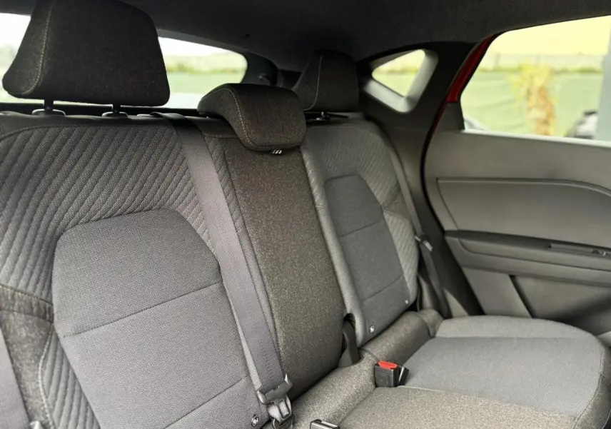 Vue latérale intérieure montrant la banquette arrière grise du Renault Captur Rouge Flamme 2026 avec appuie-têtes et ceintures de sécurité.