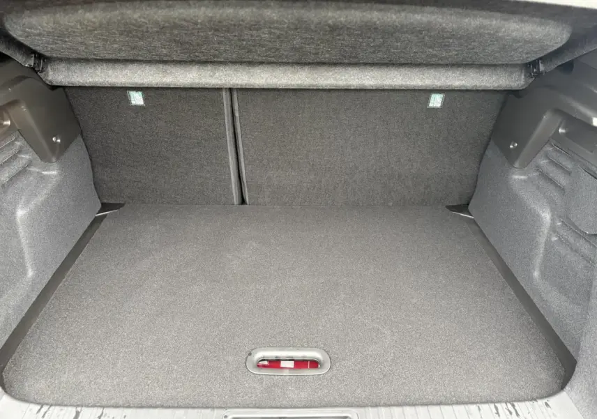 Coffre ouvert du Renault Captur rouge Flamme, vue intérieure montrant le plancher de coffre mobile et les côtés en tissu gris.