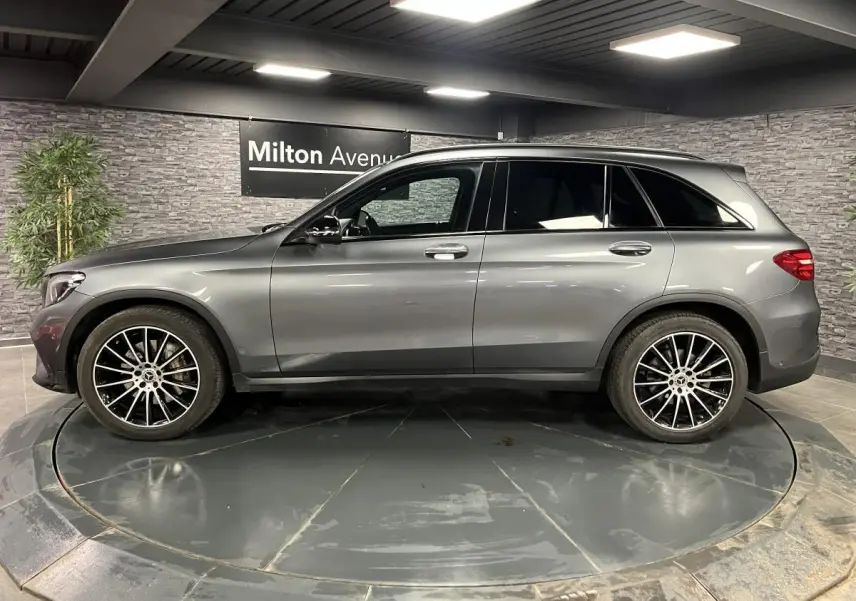 Profil droit d'un Mercedes GLC gris métallisé 2019 avec jantes alliage AMG 20 pouces multibranches dans un showroom.