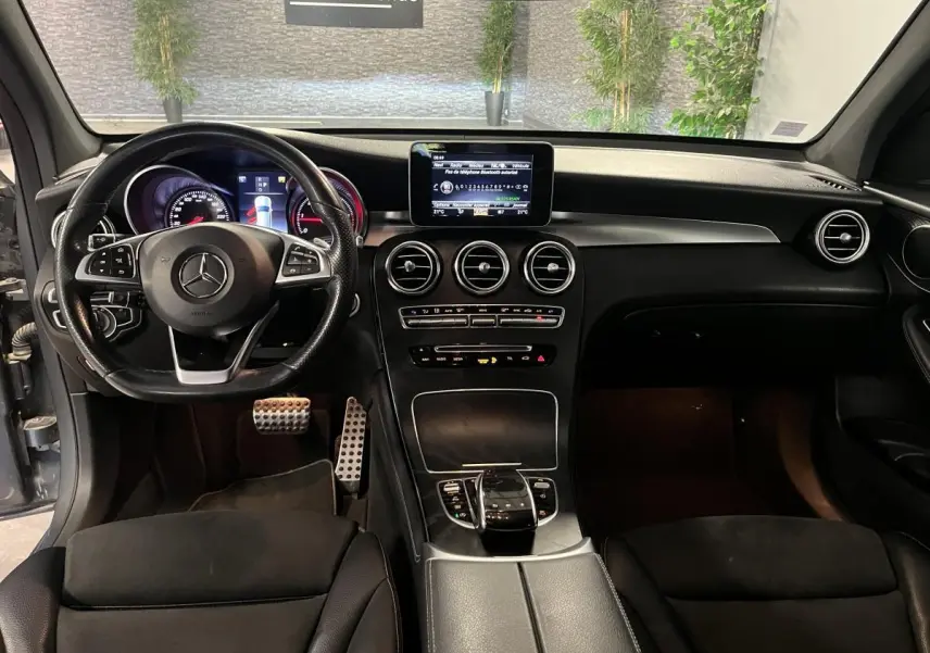 Vue intérieure avant du Mercedes GLC 220 d Sportline 2019 avec volant cuir, console centrale noire et écran multimédia.